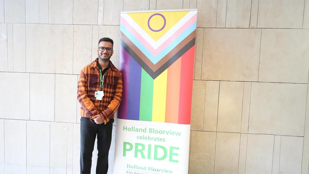 Rajpreet (Raj) Singh Sandhu standing in front of a flag