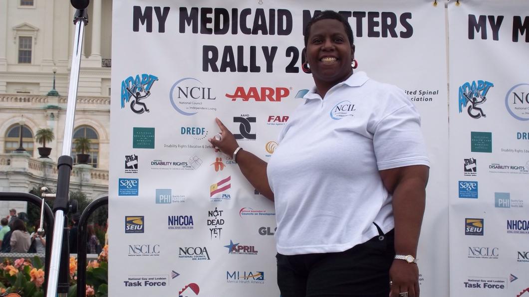 Woman stands in front of large sign that says My Medicaid Matters