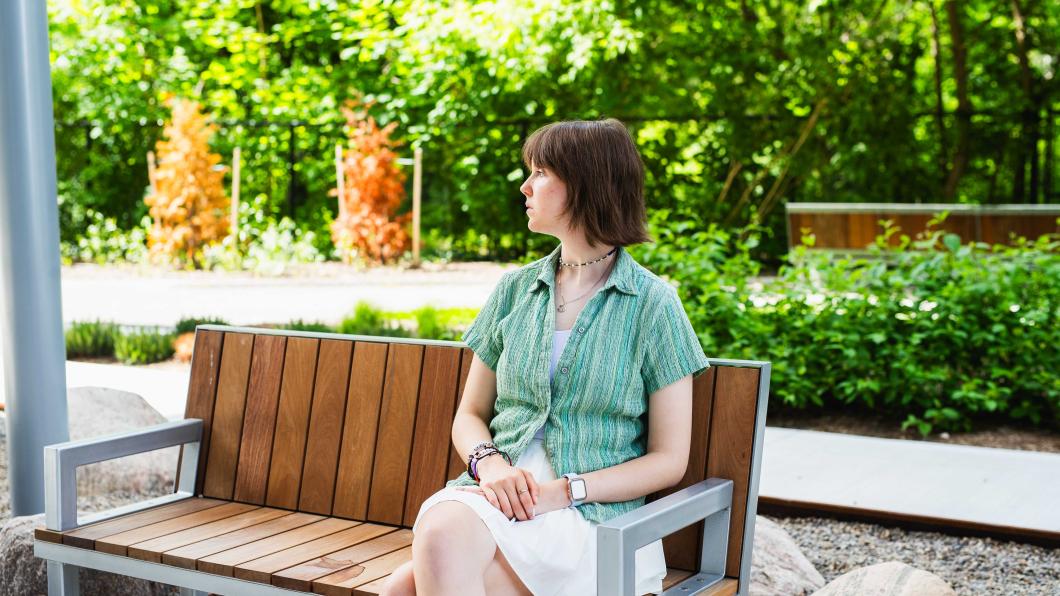 Katie sitting on a bench looking into the distance.