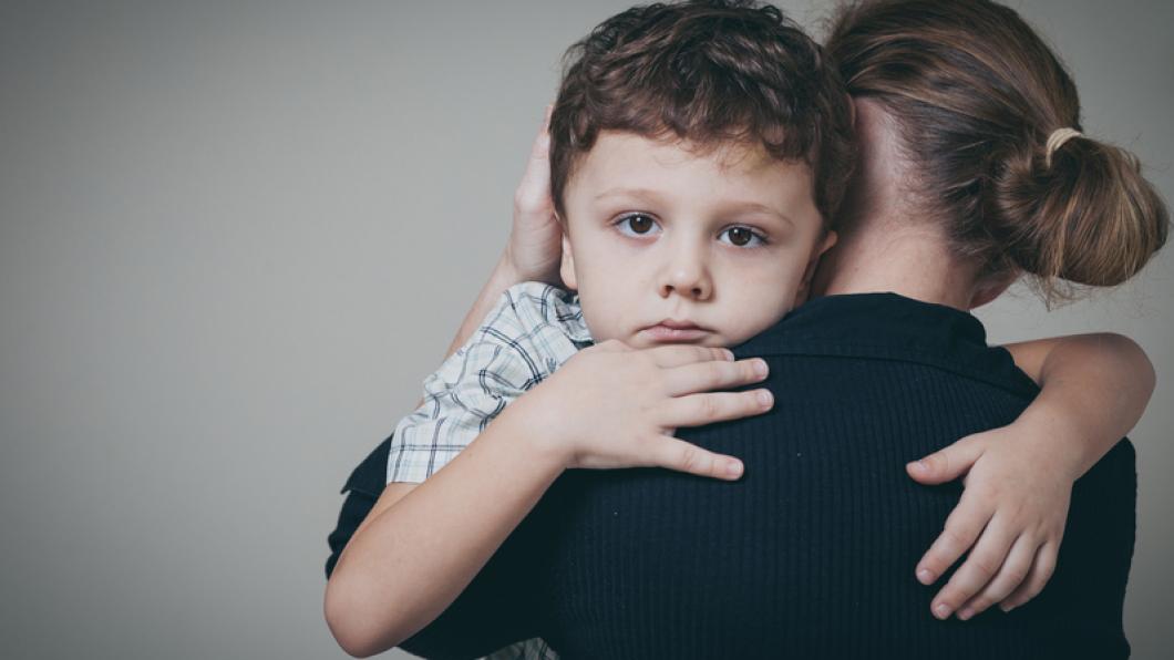 Sad young boy being held by a woman