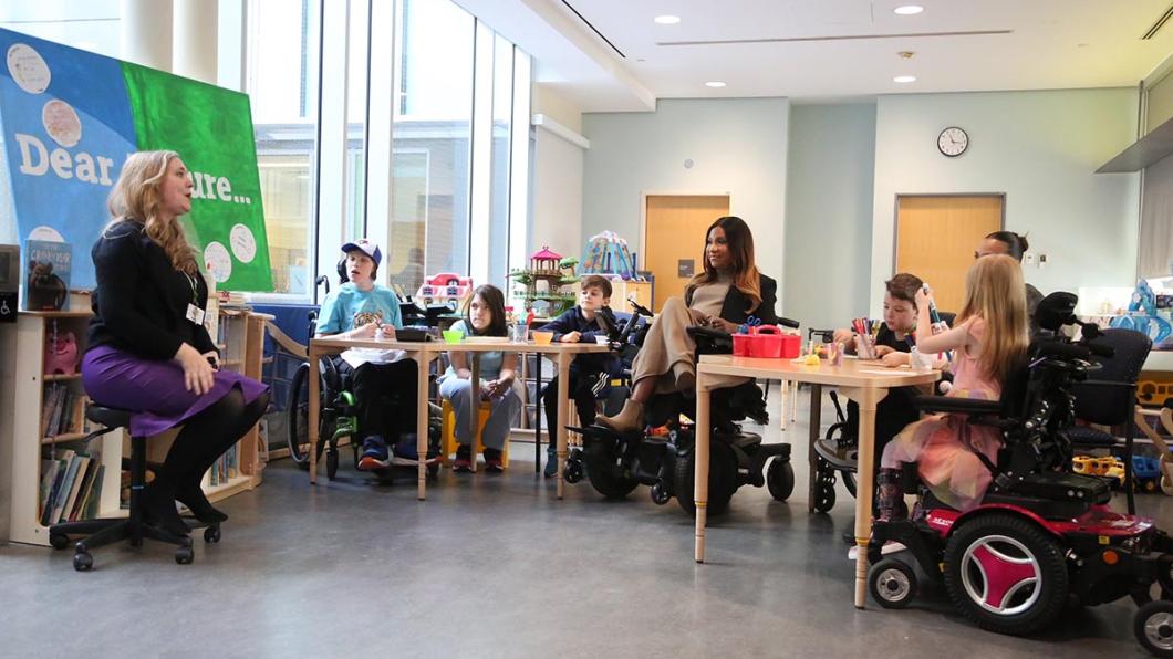 An adult is giving a talk to some children and two adults in an indoor setting