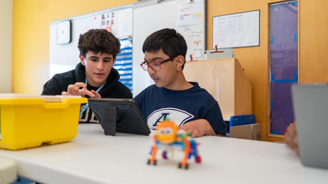 A teenager is helping a child to build a construction toy