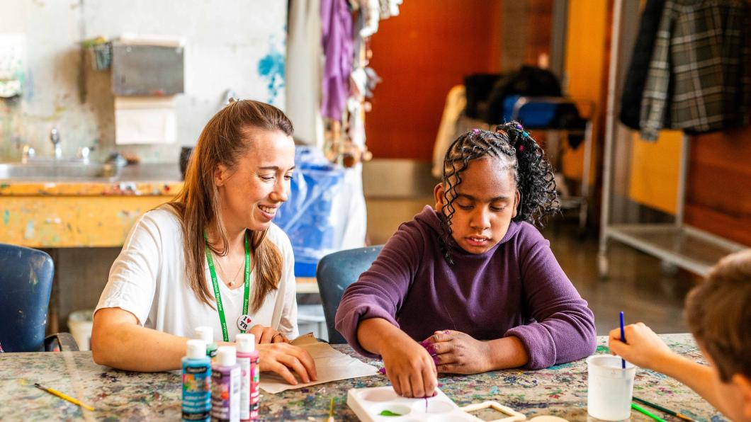 Tayah and a staff member seated at a table, painting