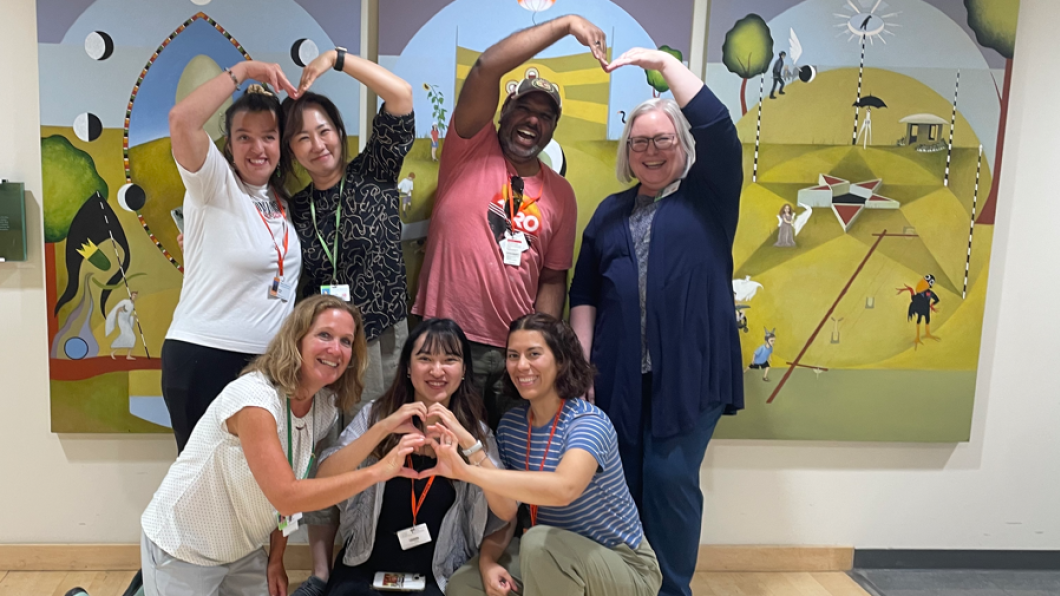 group of adults are smiling and posing for a photo against artwork in the background