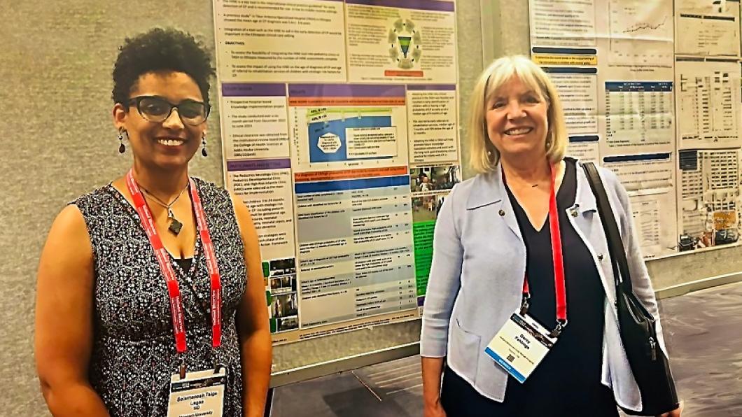 Dr. Selamesh Tsige-Legas and Dr. Darcy Fehlings stand in front of a research poster