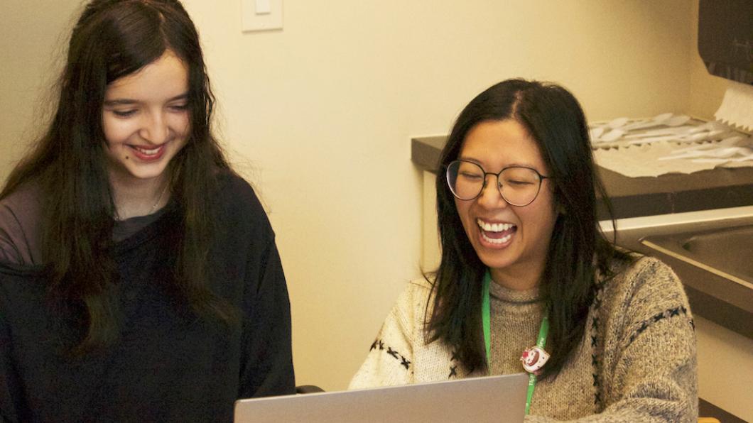 Teen girl and woman laugh at computer screen