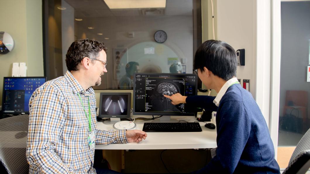 Two adults looking at an image of a brain scan on a computer screen