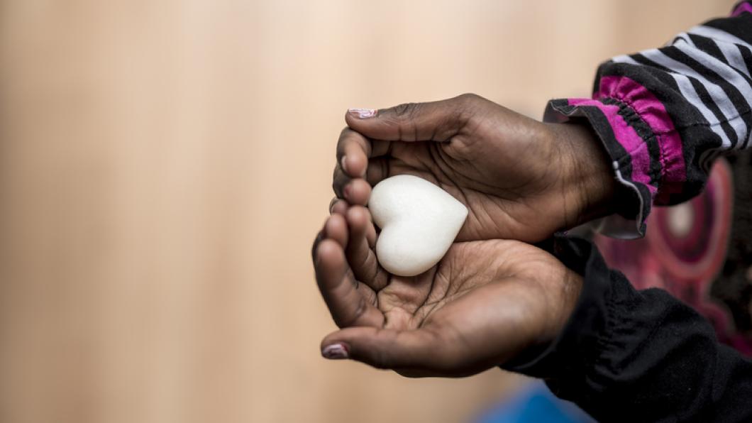 Hands hold a white heart shaped object