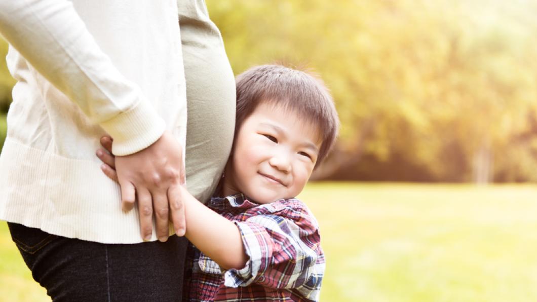 Boy hugs belly of pregnant woman