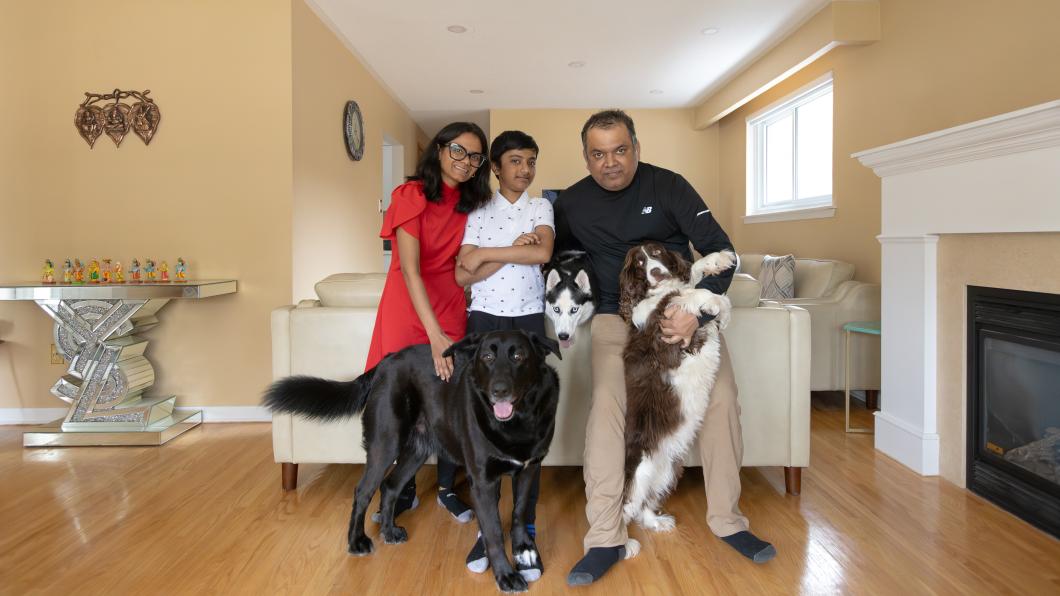Boy in the middle of woman and man with three dogs