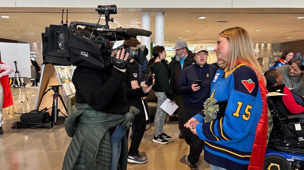 An adult is being interviewed by a camera reporter