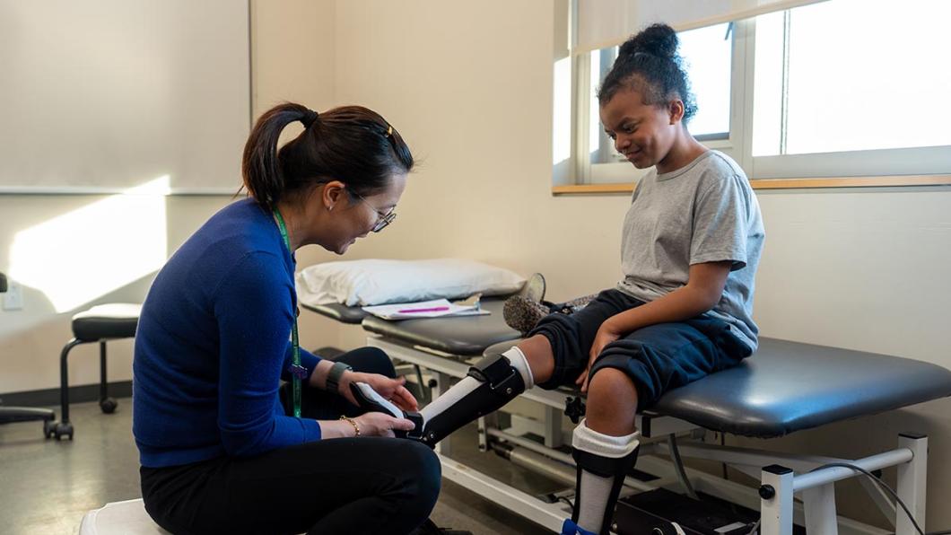 An adult helps a kid to put on the orthotic leg 