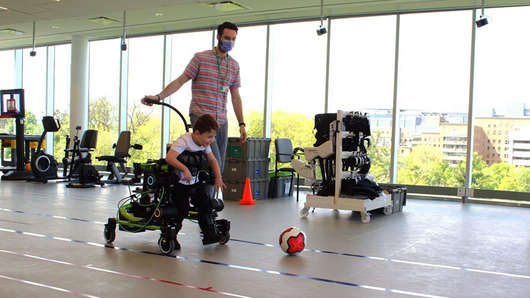 A child using the Trexo to kick a soccer ball indoors