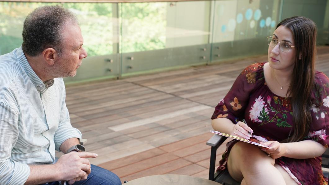 Woman with clipboard sits across from man