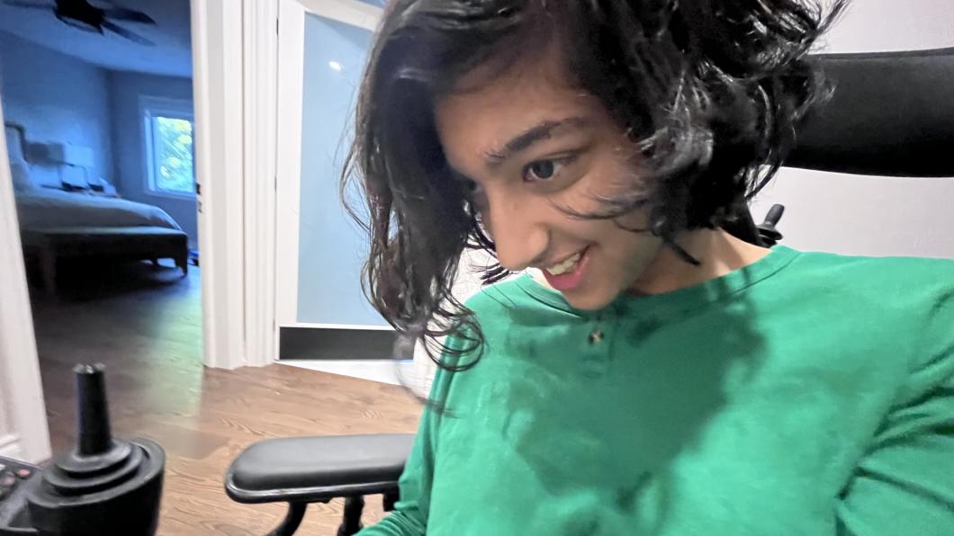 Teen with dark wavy hair and green shirt smiles