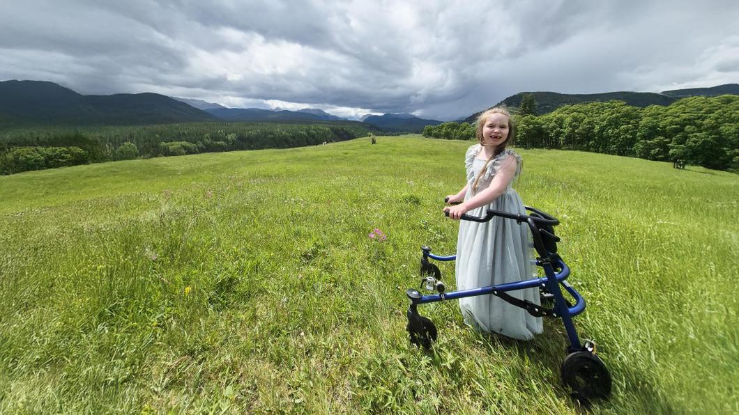 A child with walker is in the grass field