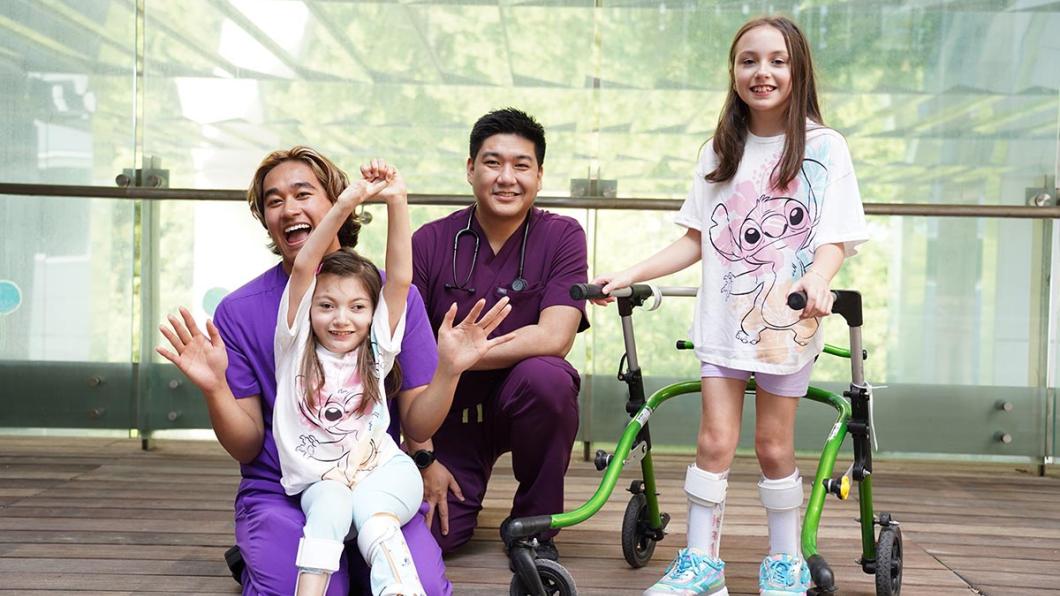 Two adults nurses are having group photos with two children patients