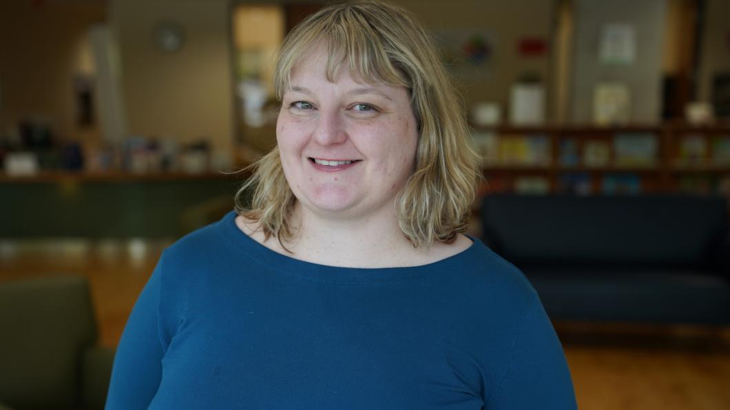 Woman with blonde hair and blue sweater in library