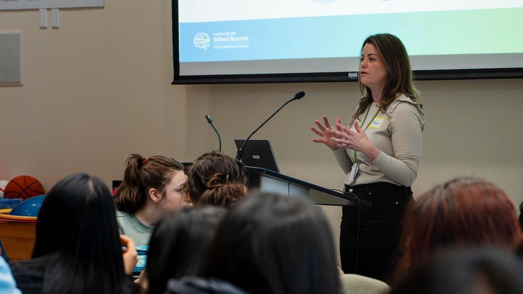 A speaker standing in front of a group of people, in a talk