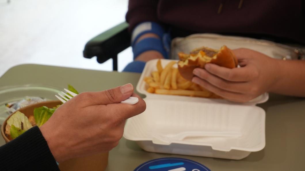A parent and child eat salad, french fries and a burger.