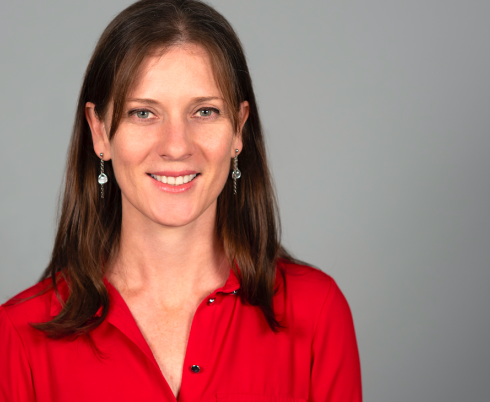 Tracey Smythe smiling at the camera, wearing a red collared shirt.