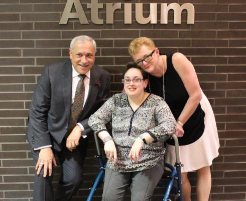 The Coriat Family posing in front of a wall with a sign that says "Coriat Atrium" in silver letters.