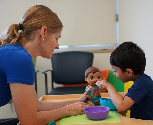An adult is playing toys with a young child