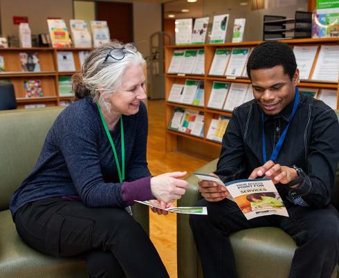 Two adults reading leaflets in a library setting