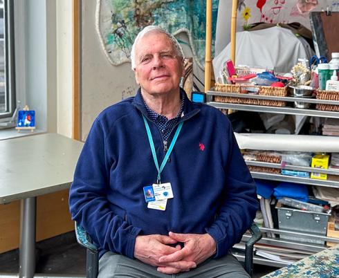 A man sits in an art therapy room with his hands in his lap. 