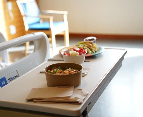 Bowls of food placed on a table in a hospital room.