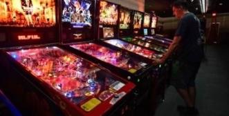 Photo of a lit up pinball machine in a dark room. Red pinball for change logo beside.