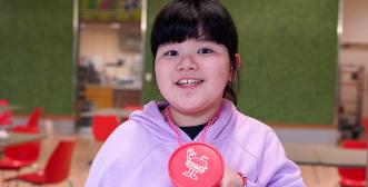 A child is holding a Rosie's Burger badge